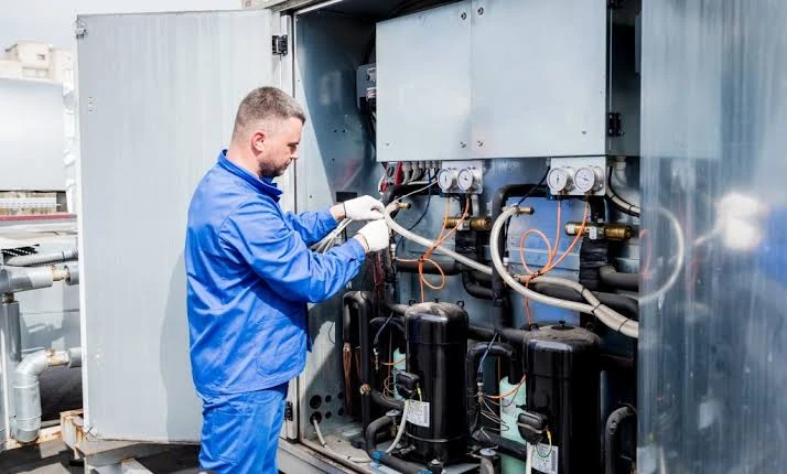 HVAC technician inspecting an open mechanical equipment cabinet