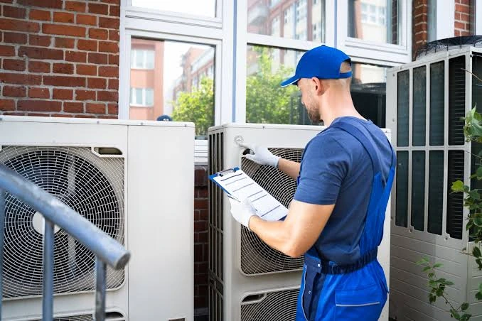 HVAC technician checking outdoor units against a maintenance checklist